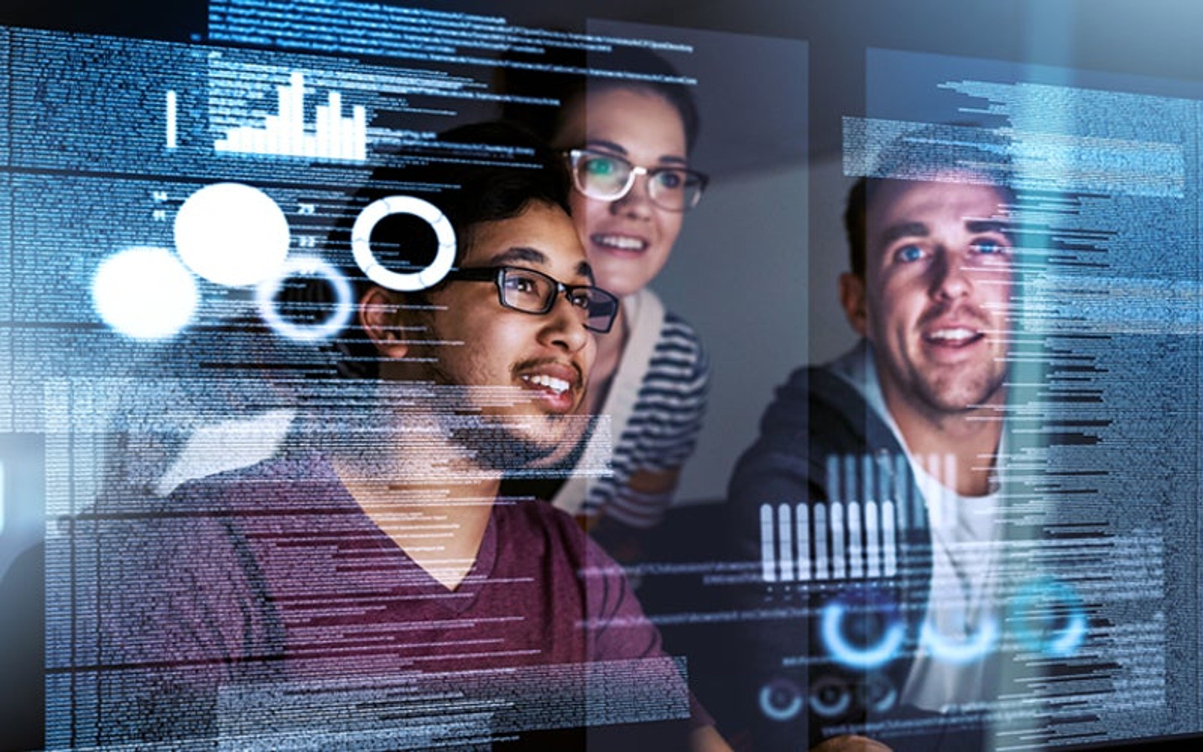 Three developers looking at code on multiple screens