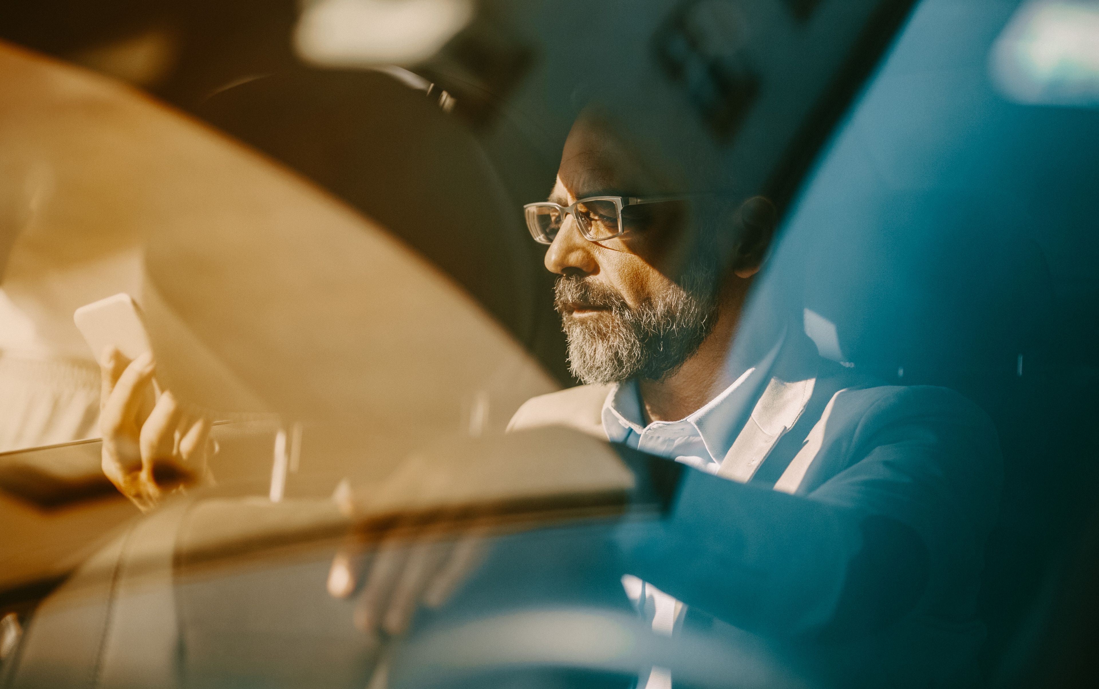 Man reading text message in the backseat of car