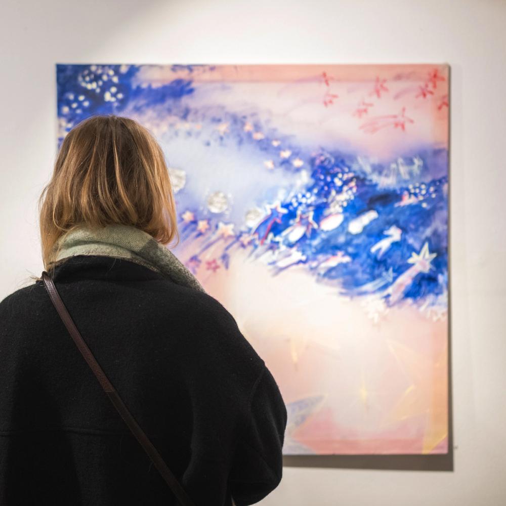 Woman standing in front of three artworks at Goldberg Gallery