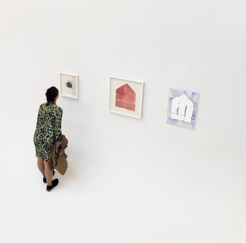 Woman standing in front of three artworks at Goldberg Gallery