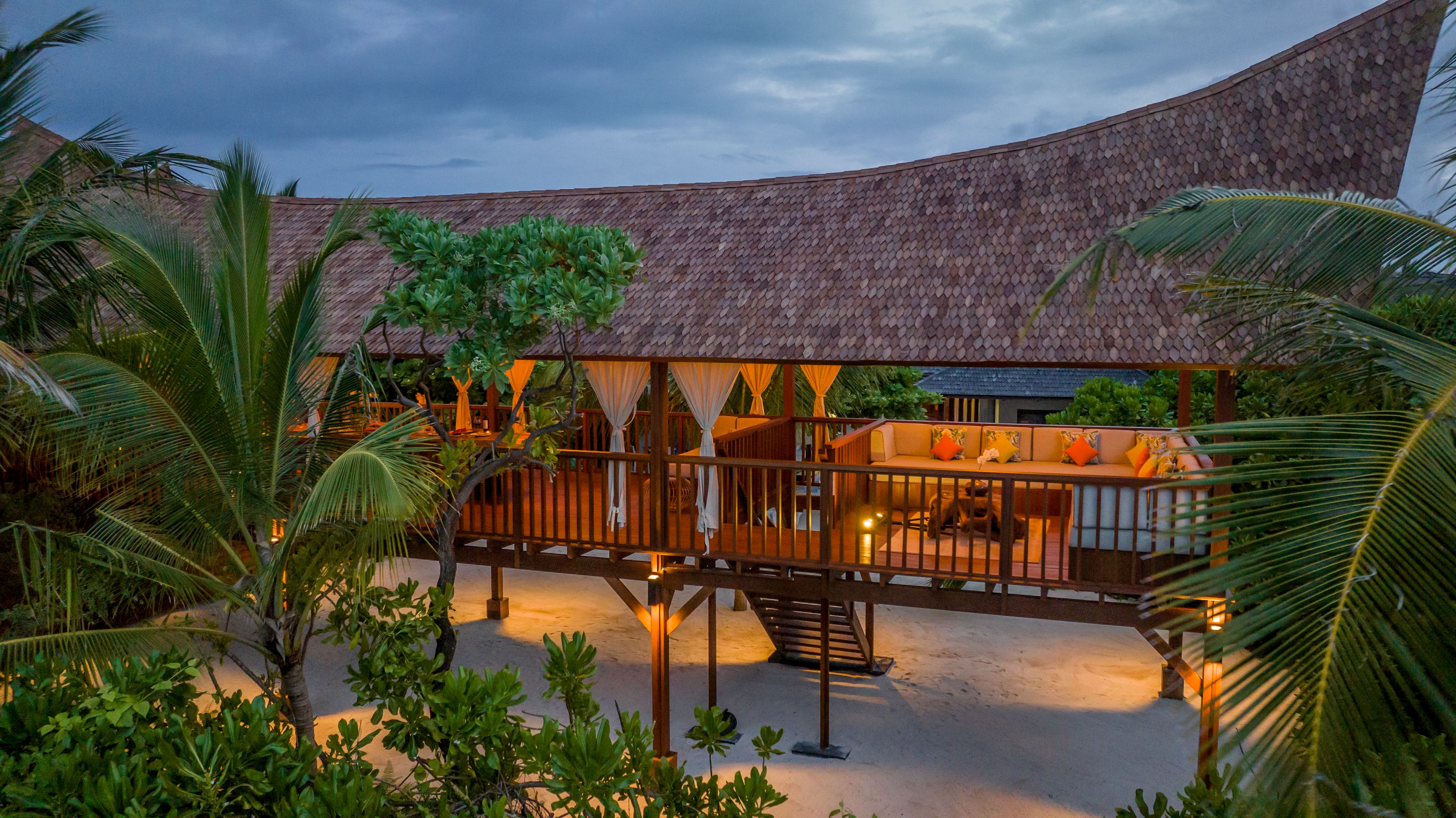 a large wooden house with a roof and a balcony surrounded by palm trees .