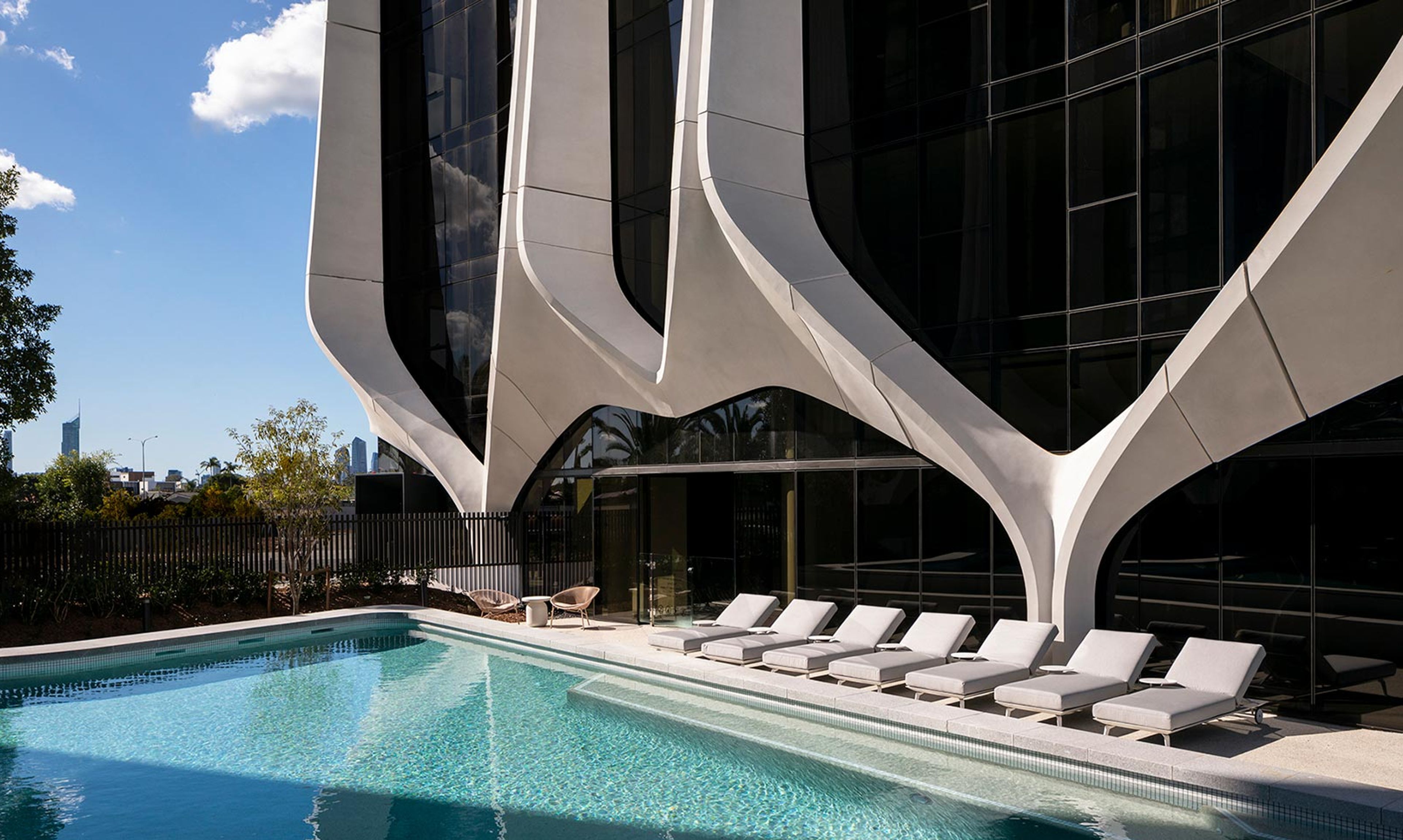 a large swimming pool surrounded by lounge chairs in front of a building .