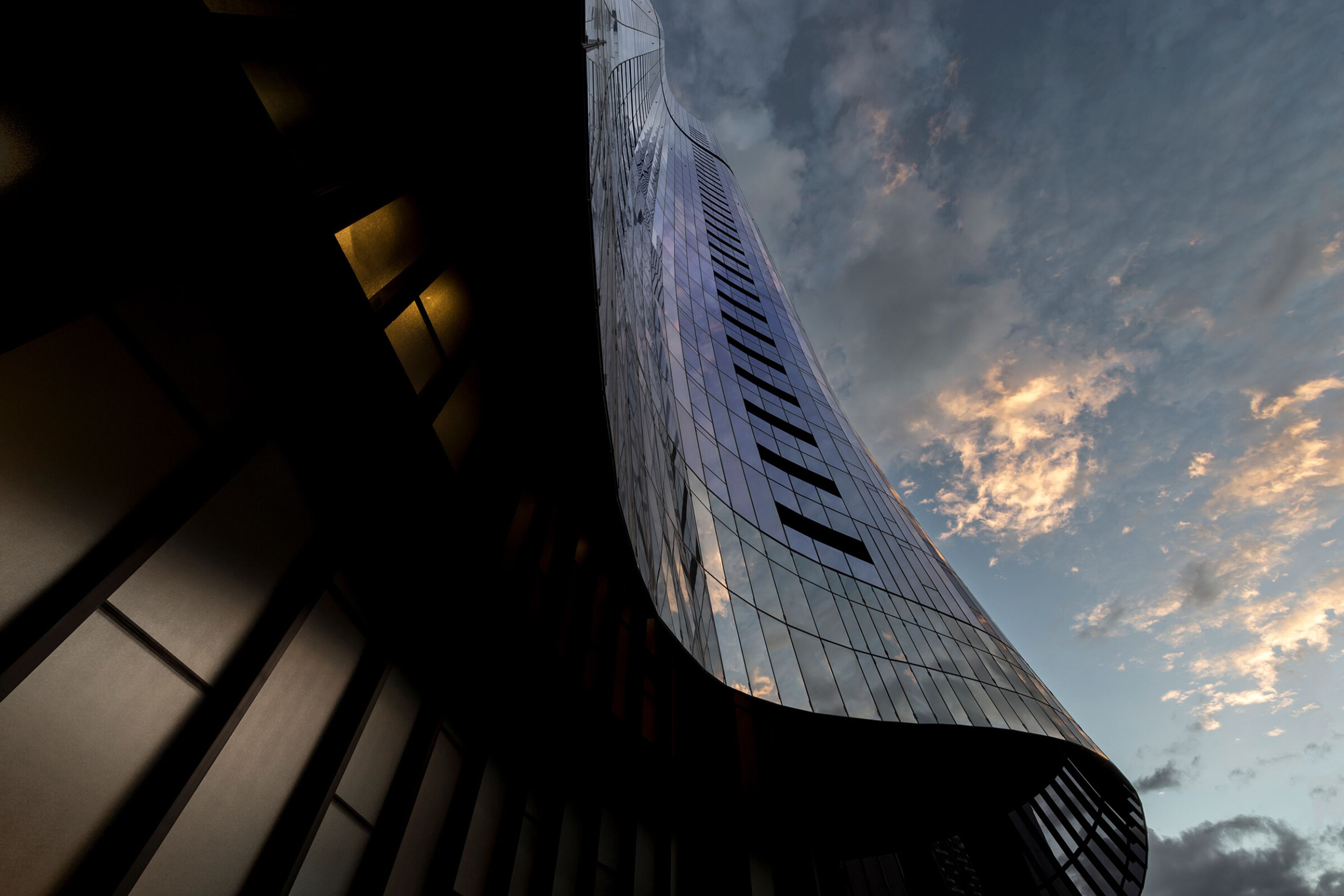 looking up at a tall building with a cloudy sky in the background .