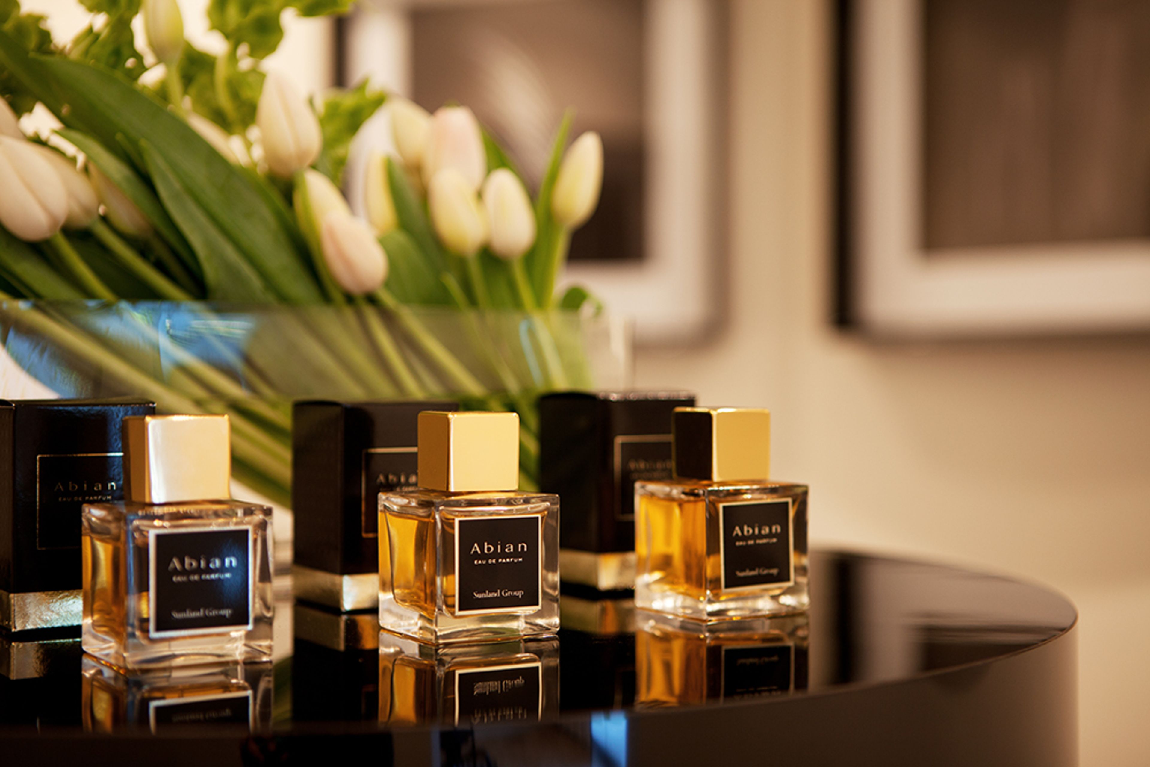 three bottles of perfume are sitting on a table next to a vase of flowers .