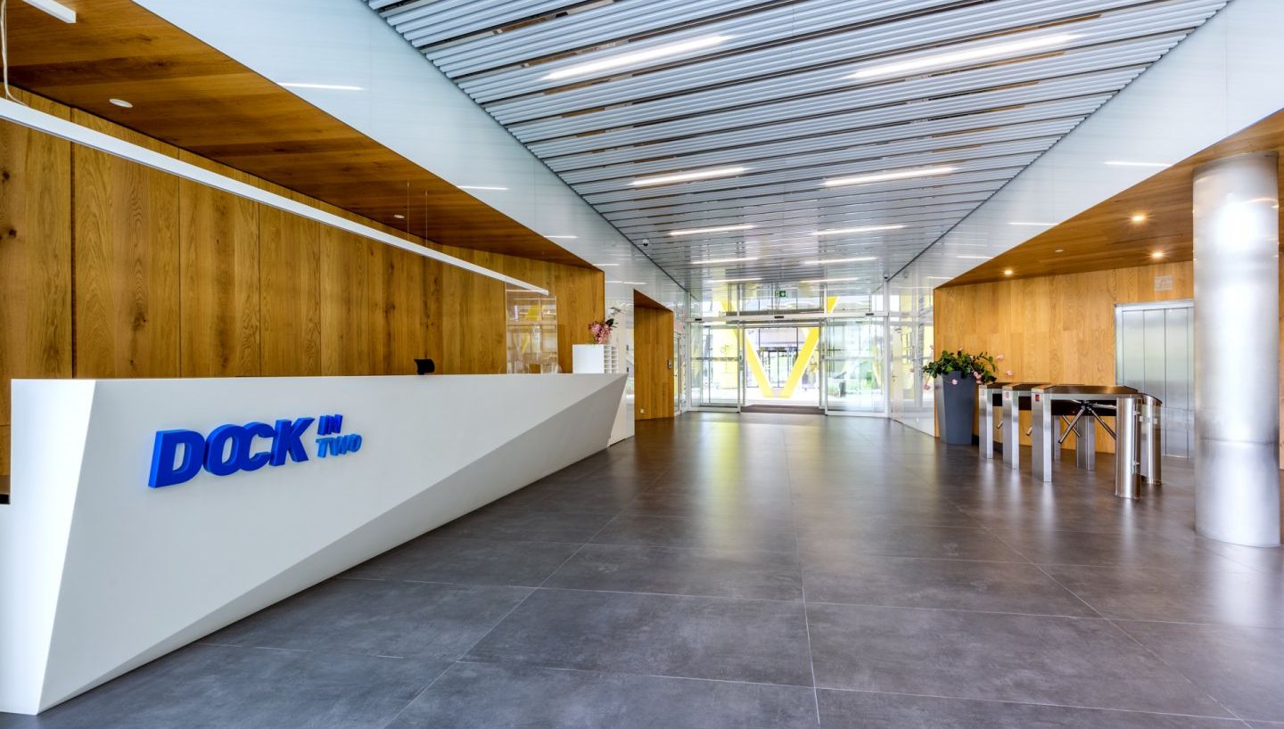 a large lobby with a lot of windows and people sitting on couches .