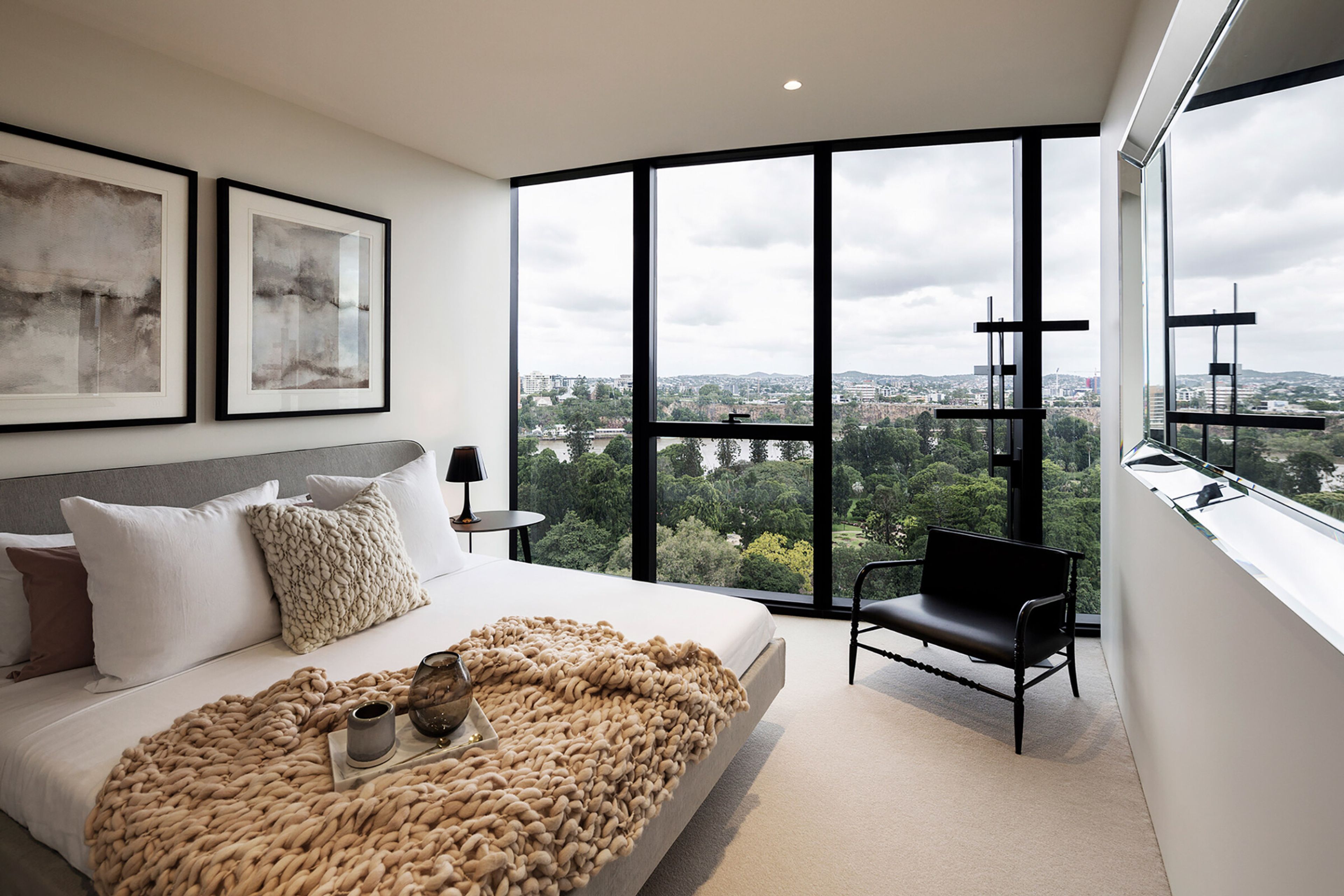 a bedroom with a bed , chair , mirror and large windows .