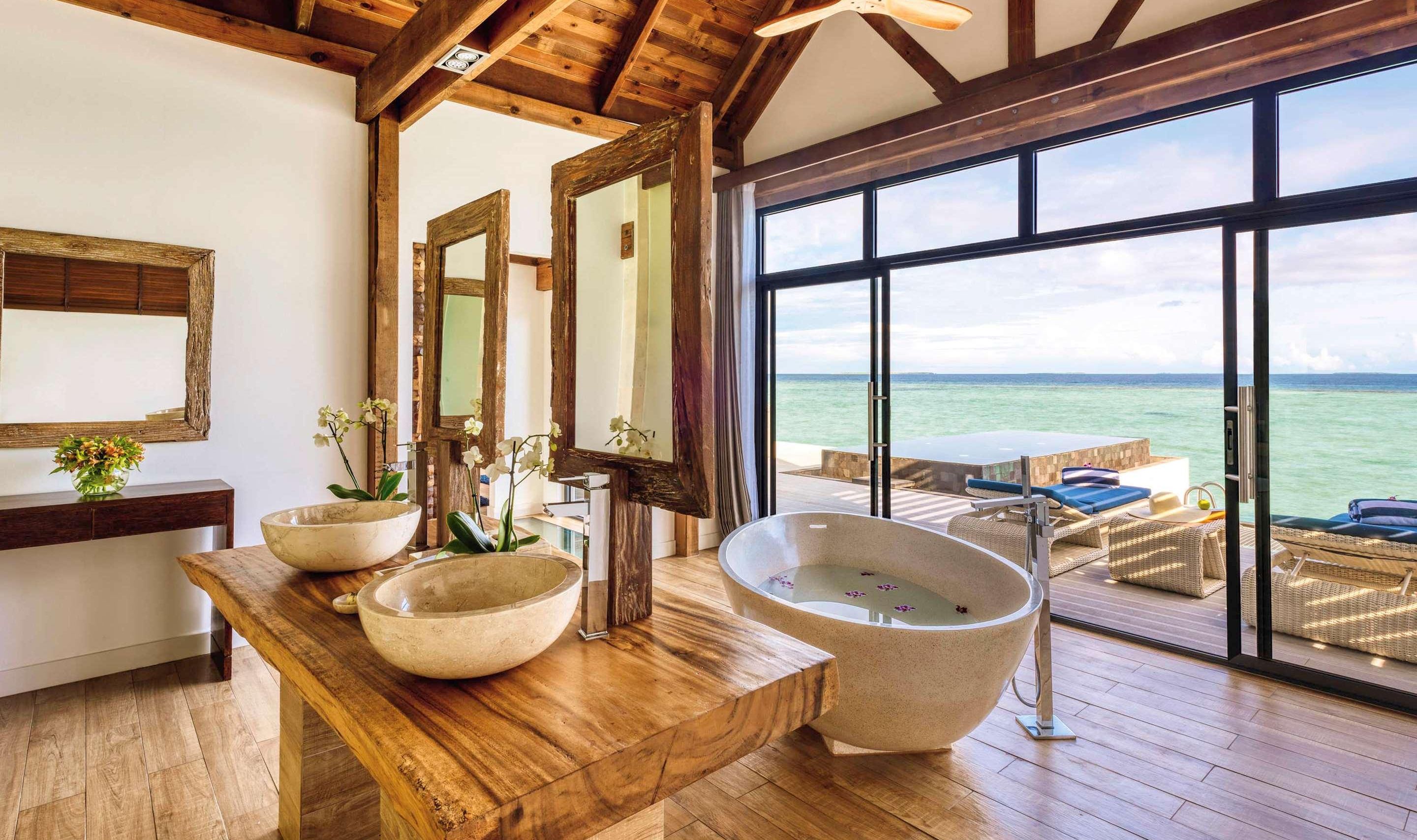 a bathroom with two sinks and a bathtub with a view of the ocean .