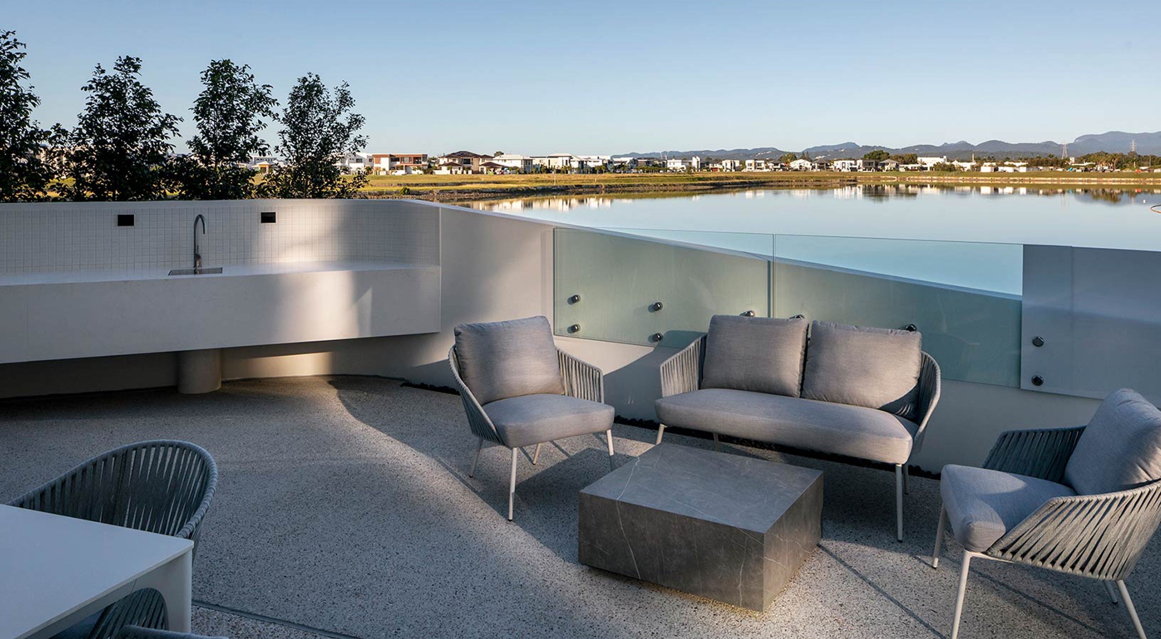 a patio with a couch , chairs , table and a view of a lake .