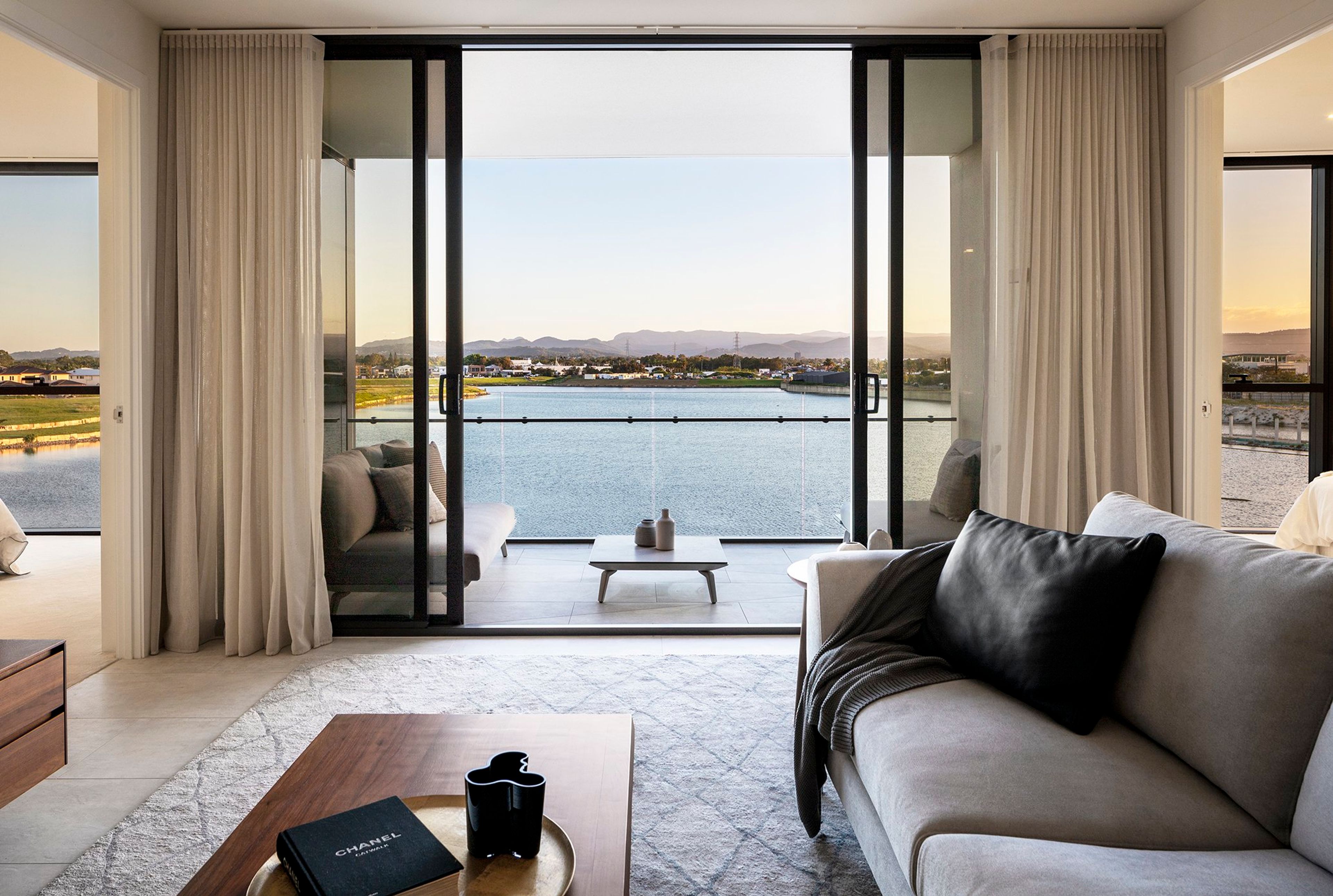 a living room with a couch , coffee table , and balcony overlooking a body of water .