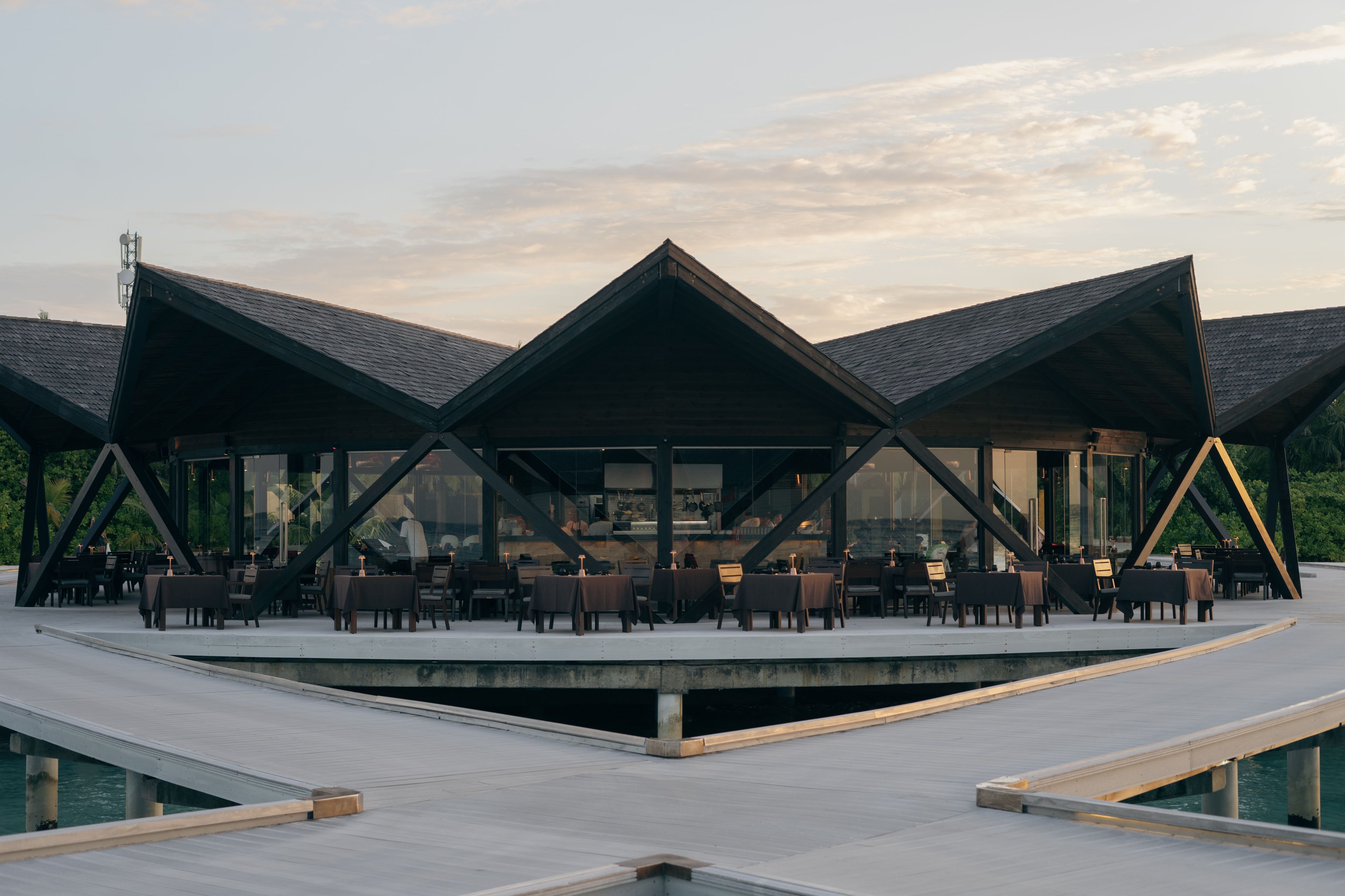 a restaurant with tables and chairs on a wooden deck overlooking the water .