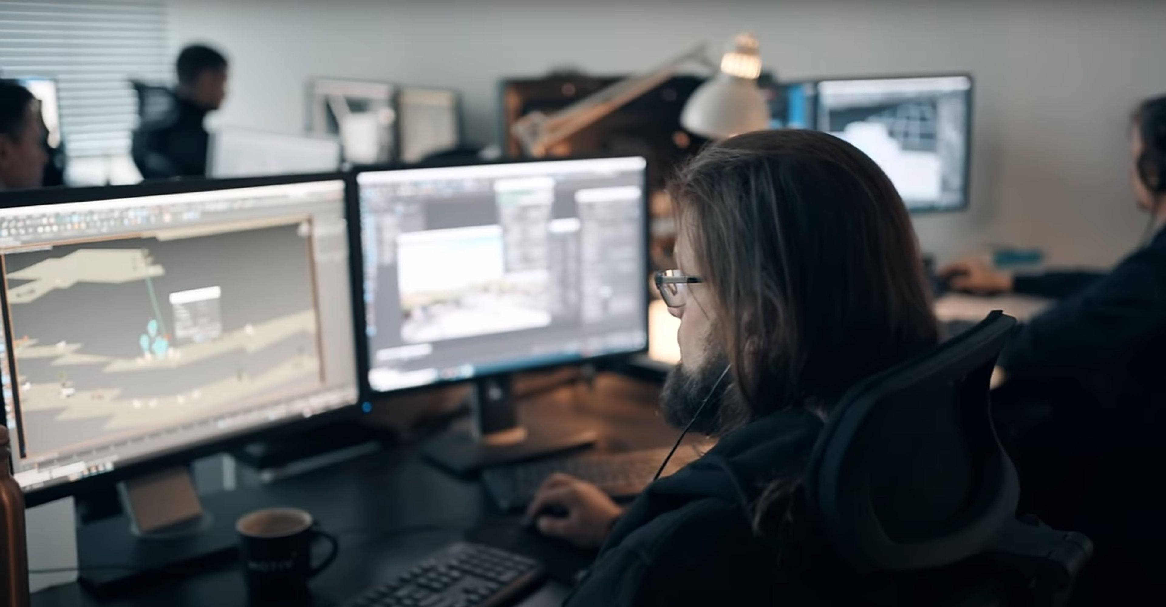 a man is sitting at a desk in front of two computer monitors .