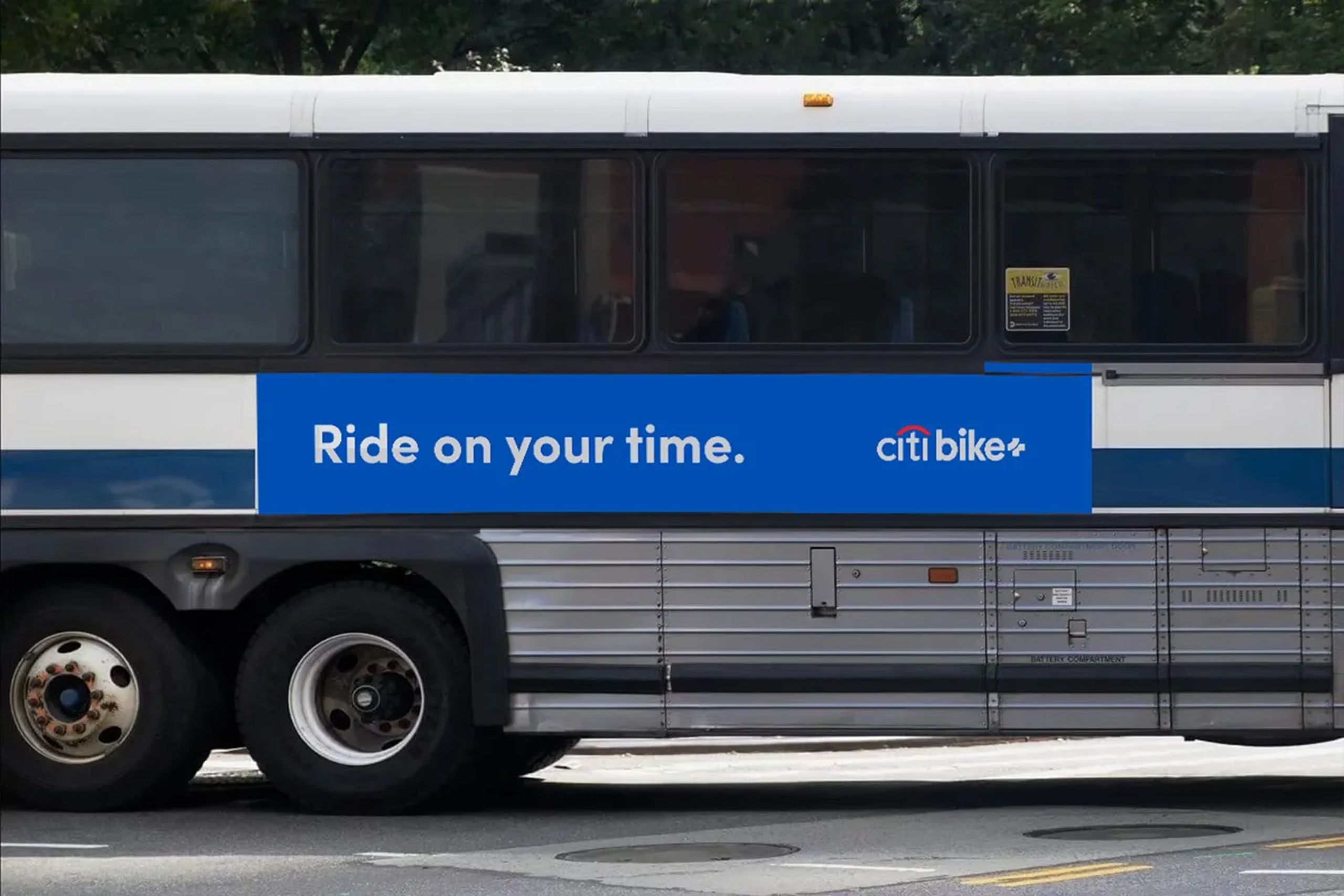 Side view of a city bus mockup featuring a Citi Bike+ advertisement with the slogan “Ride on your time” on a bold blue banner, promoting flexible commuting options.