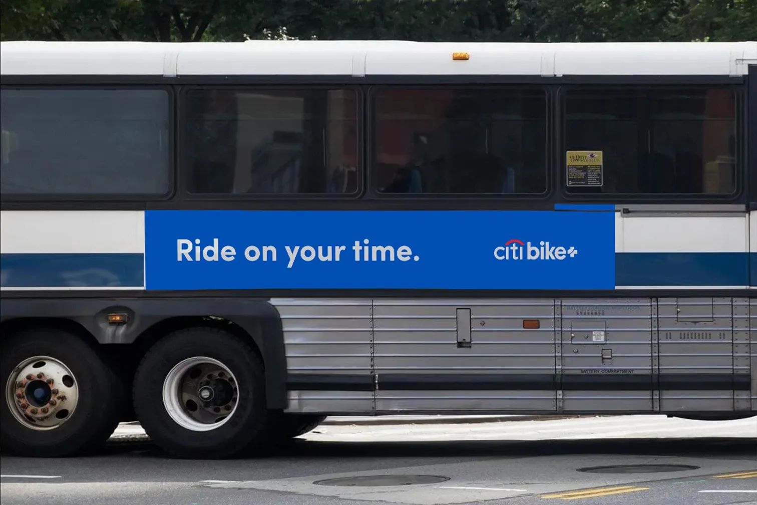 Side view of a city bus mockup featuring a Citi Bike+ advertisement with the slogan “Ride on your time” on a bold blue banner, promoting flexible commuting options.