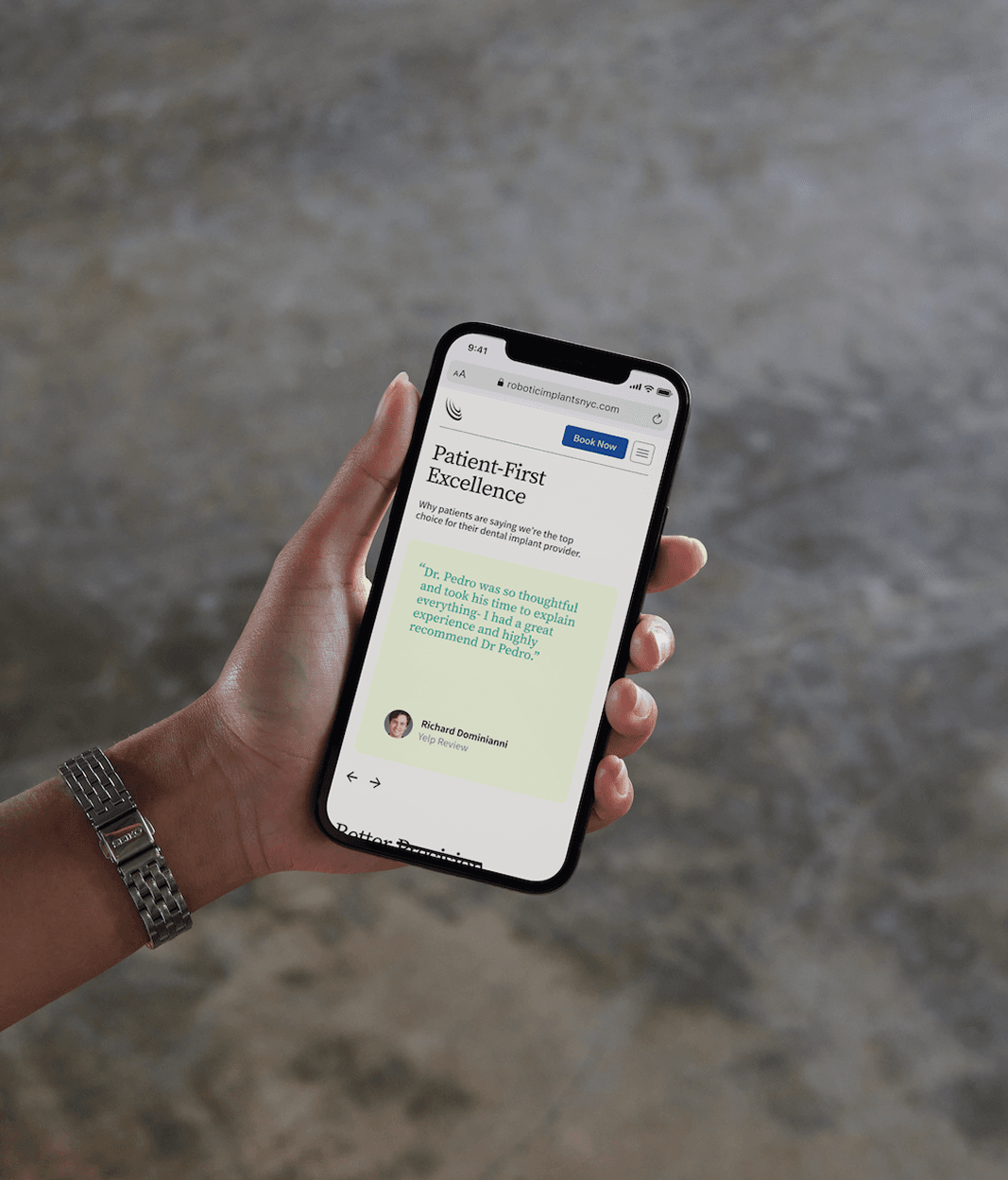 The Robotic Implant Center website on a phone held in one hand, showing a "Patient-First Excellence" page. Presentation mockup.
