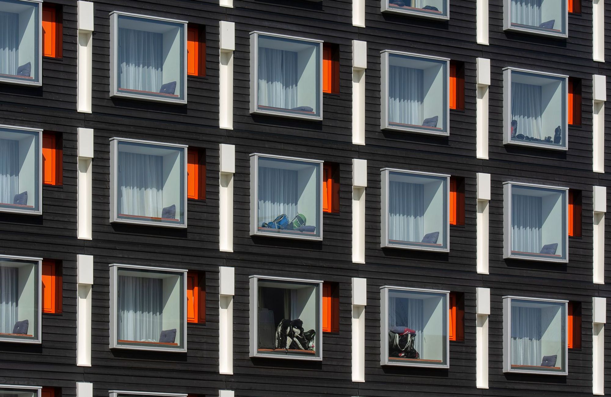 Close-up of a modern hotel facade with uniform geometric windows featuring colorful accents. (Foto: Jan van der Wolf / Pexels)