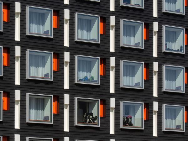 Close-up of a modern hotel facade with uniform geometric windows featuring colorful accents. (Foto: Jan van der Wolf / Pexels)