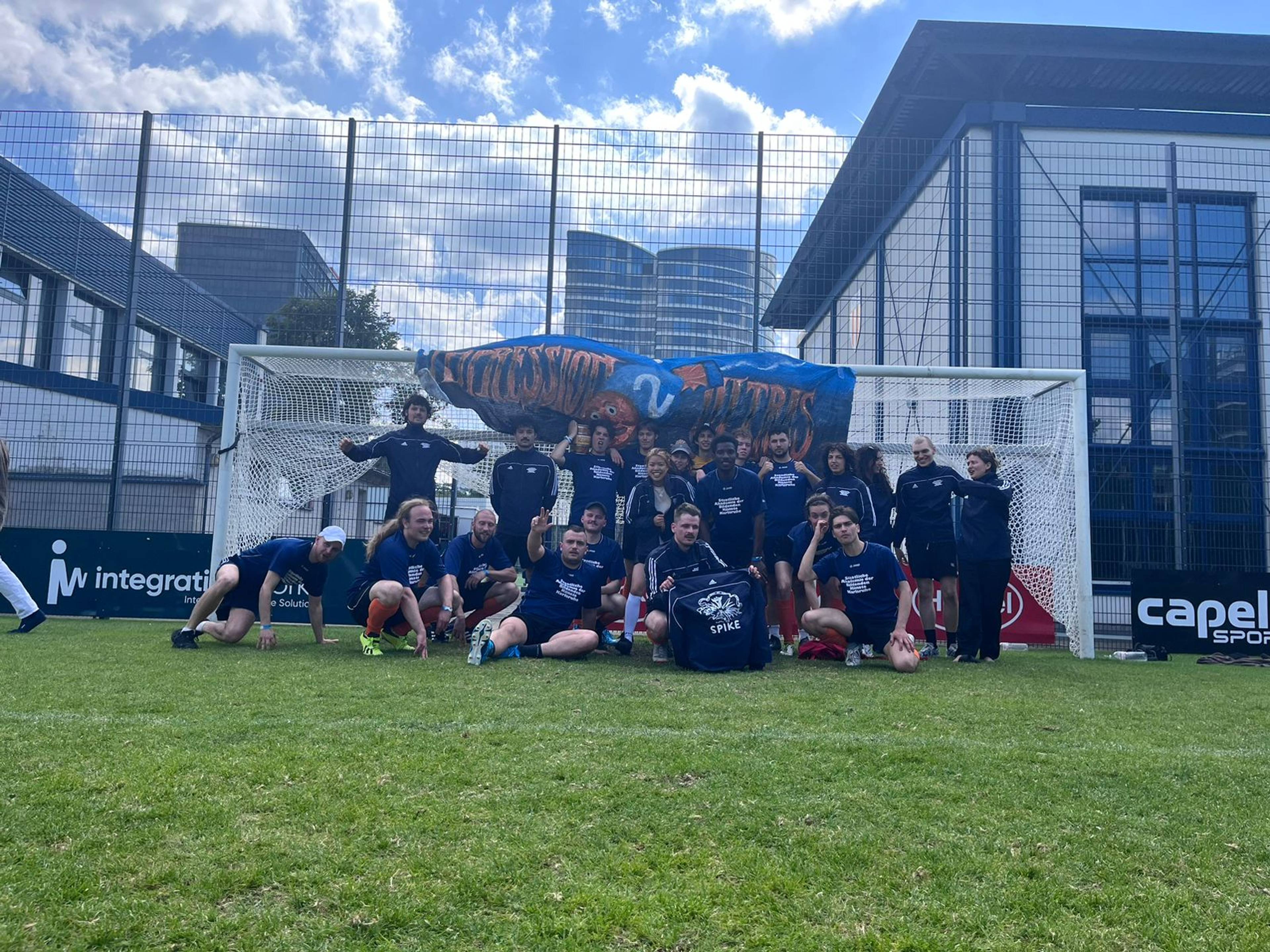 Team of the Karlsruhe Art Academy on a green pitch, dressed in SPIKE jackets