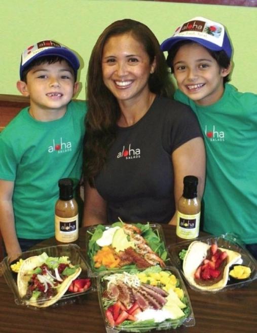 Sara Lufrano with her two young sons wearing Aloha Salads caps, with fresh salads and dressings
