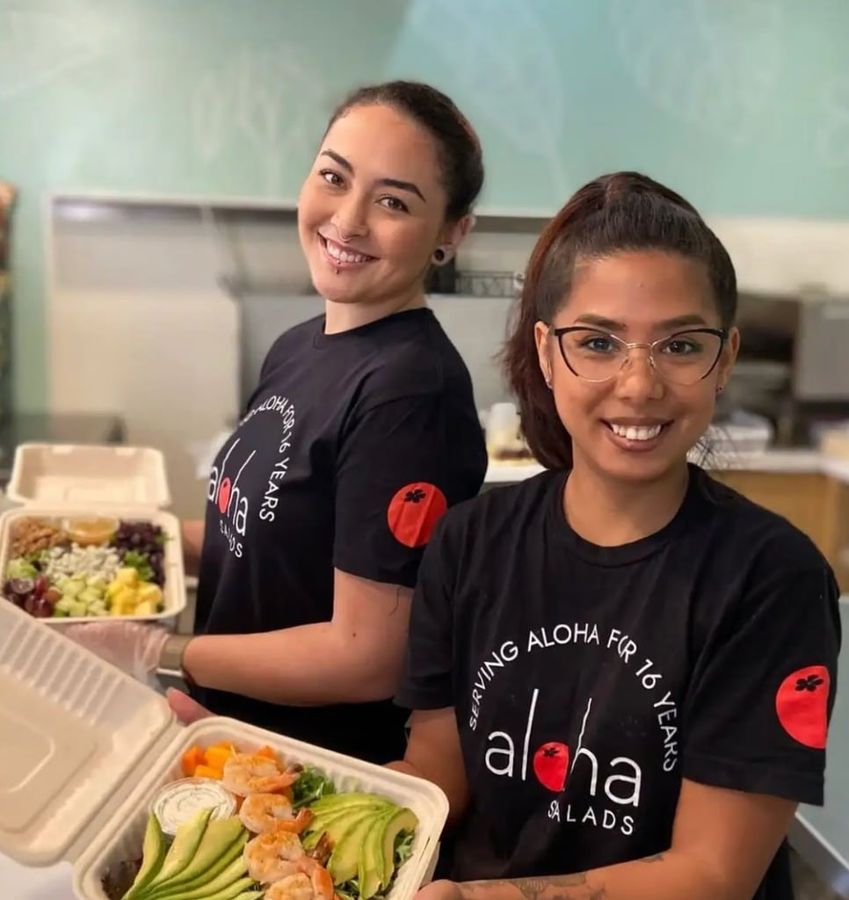Two Aloha Salads team members smiling and holding fresh salad boxes