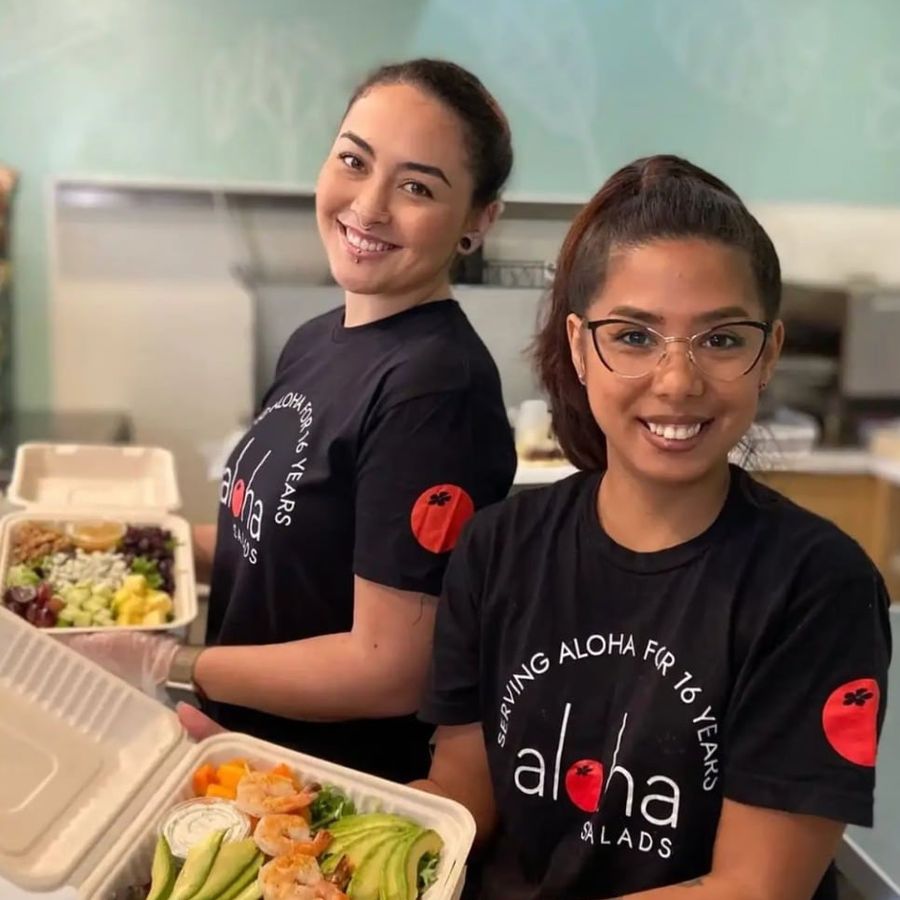 Two Aloha Salads team members smiling and holding fresh salad boxes Two Aloha Salads team members smiling and holding fresh salad boxes