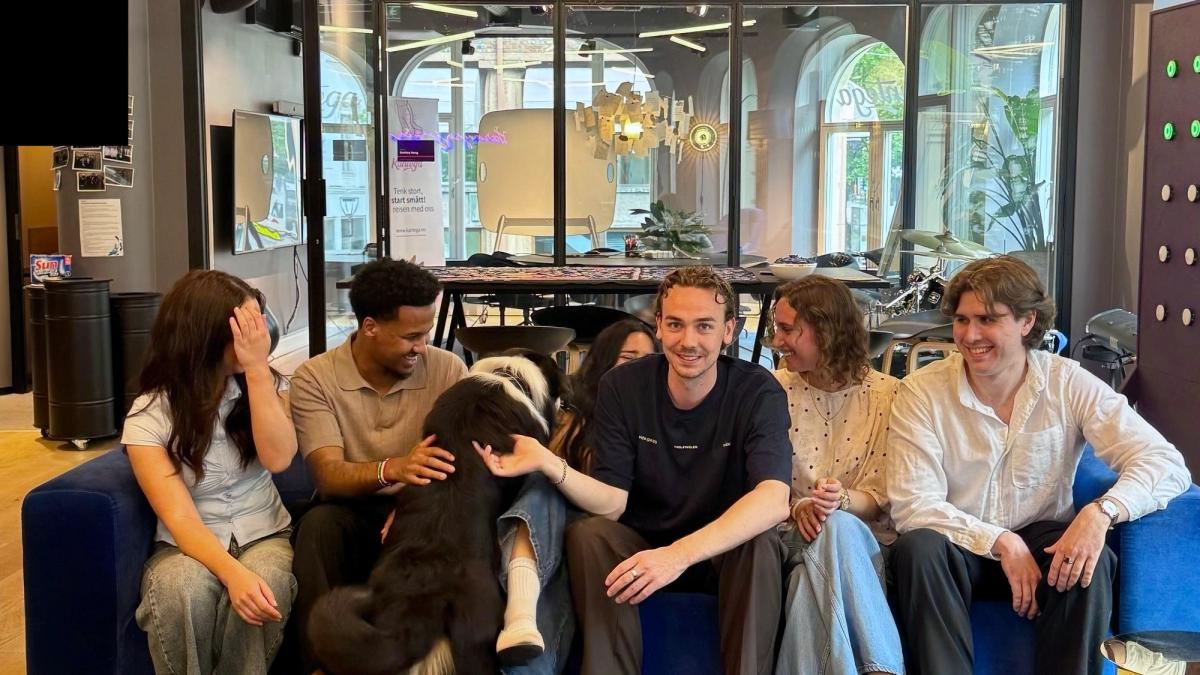 Studentene sitter i sofaen sammen med hunden Zarko