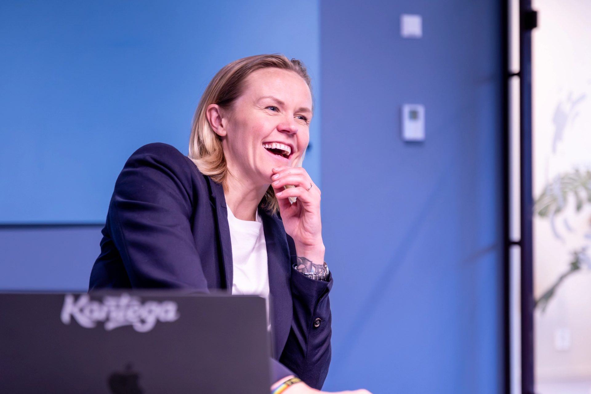 Smilende kollega i et møterom med en Kantega-PC foran seg