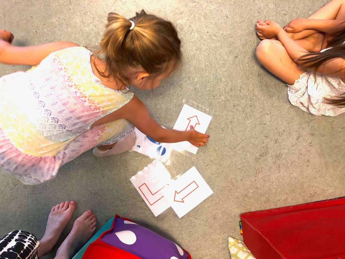 et barn plukker opp et av flere ark med en pil på