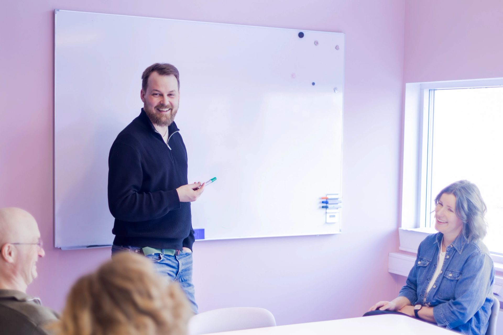 Kollega presenterer ved en tavle for kolleger i et møterom