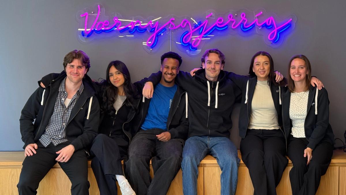 Studentene samlet foran "Vær Nysgjerrig" veggen i Kantega hettegensere