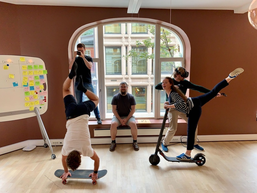 Studentene som poserer med skateboard, sparesykkel, VR-briller og kamera