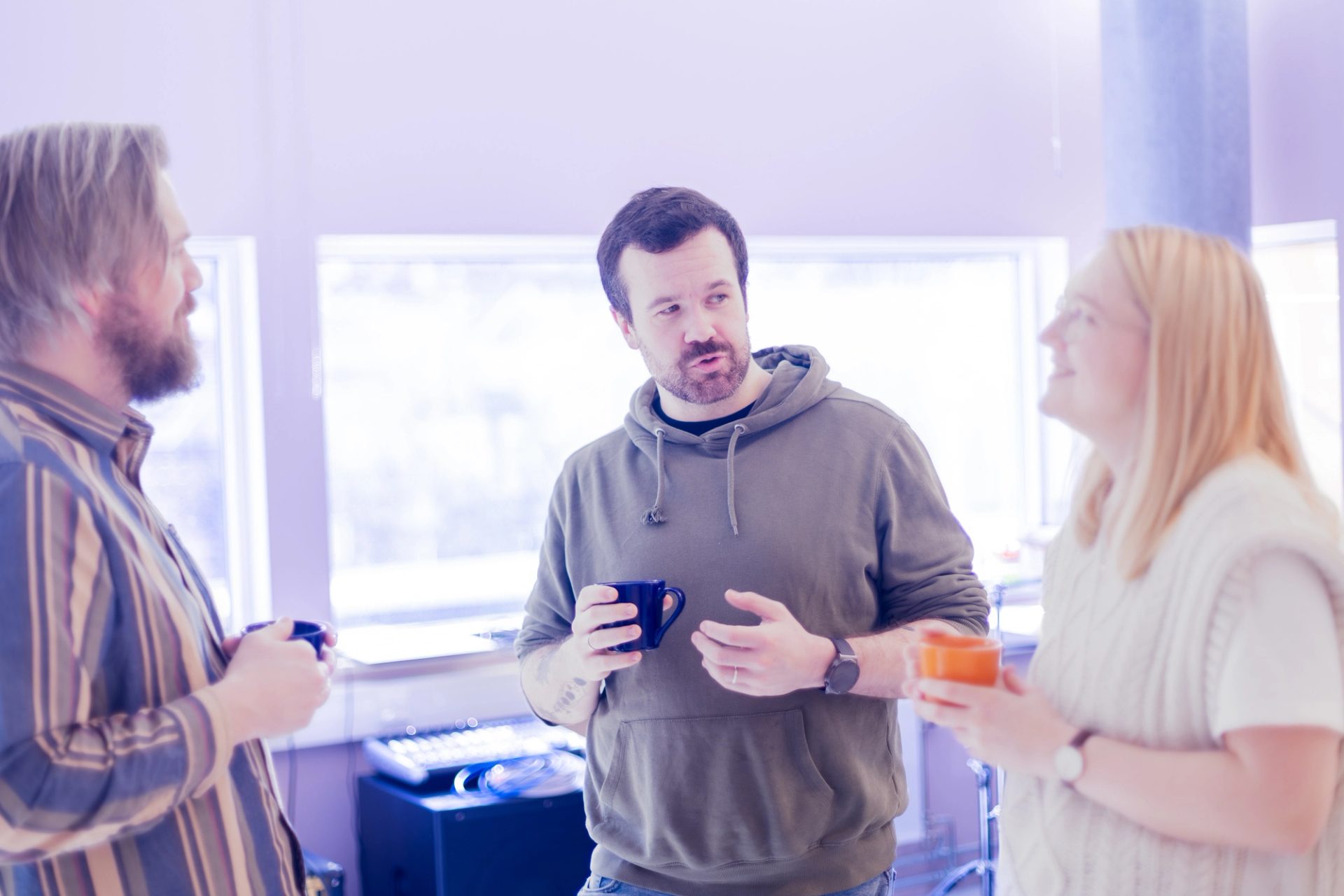 Tre kolleger i en uformell prat med kaffekopper