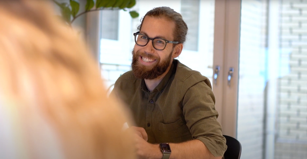 Bilde av ansatt i Kantega som diskuterer rundt bordet. Smiler og god stemning.