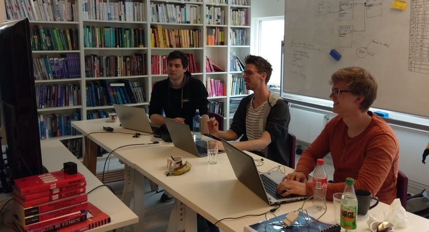 Tre unge menn som mob-programmerer foran en felles skjerm.