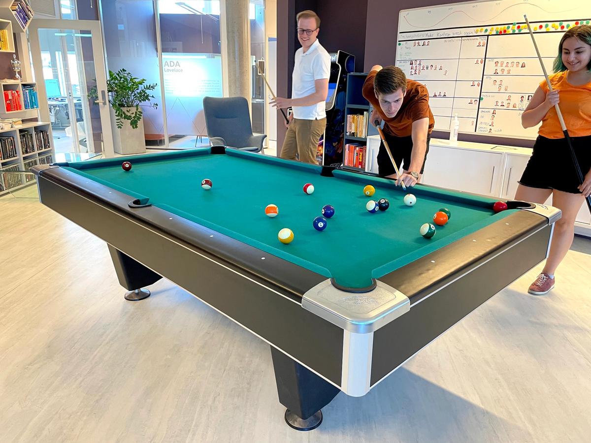 Studentene samlet rundt biljardbordet mens Magnus gjør seg klar til å slå..