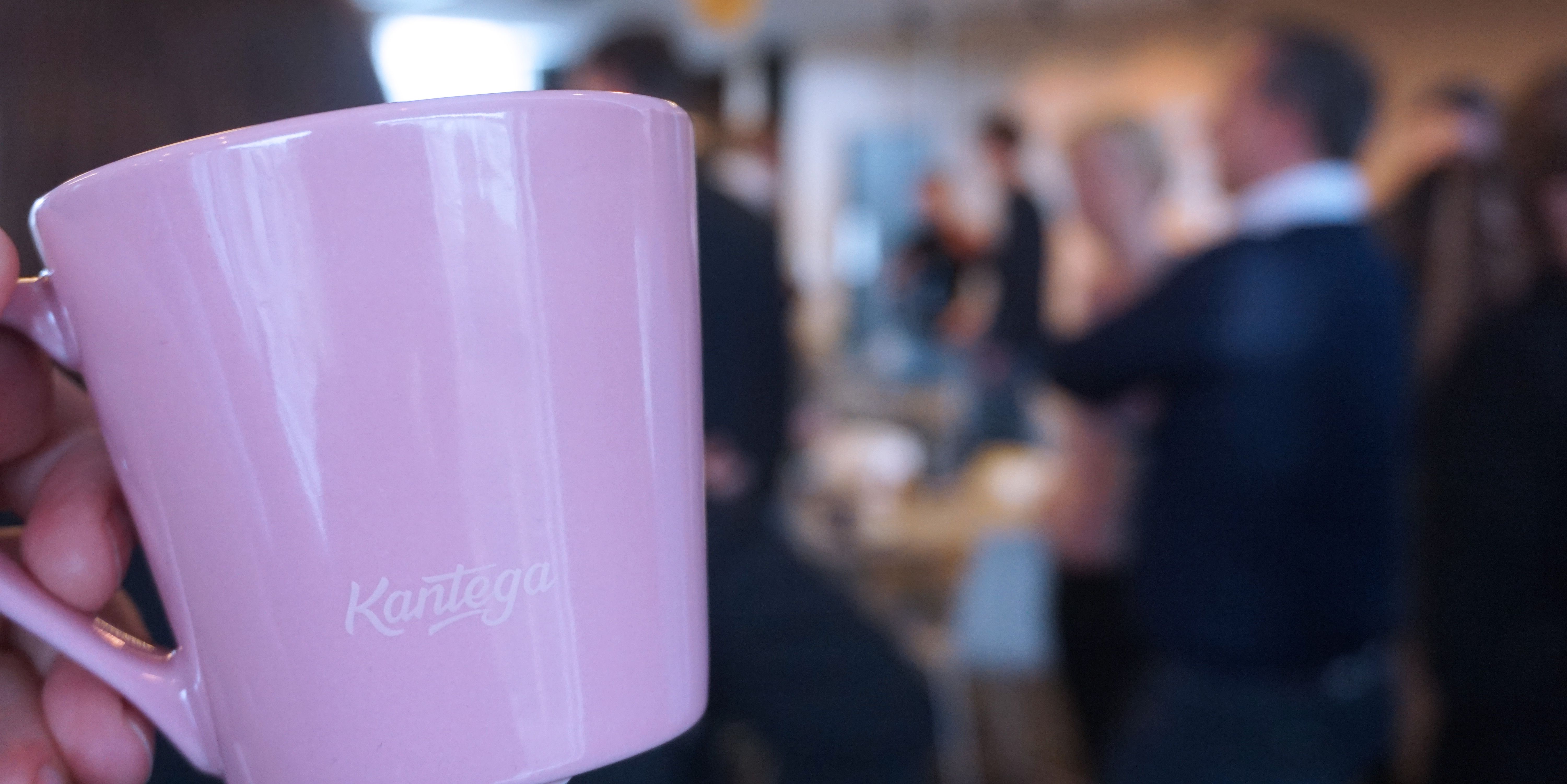 Rosa kaffekopp, og mennesker i bakgrunnen