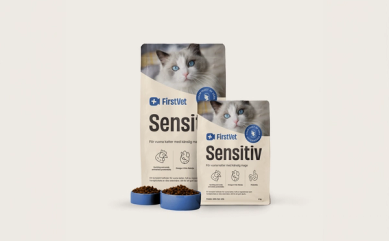 Påsar med kattmat från FirstVet Sensitiv. Med blåa, fyllda matskålar framför.