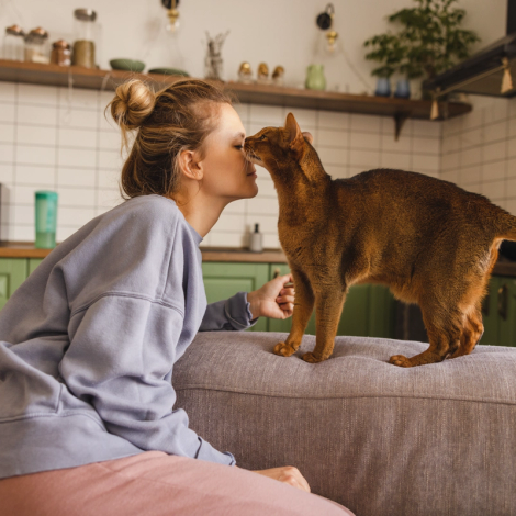 En kvinna gosar med sin katt i köket.