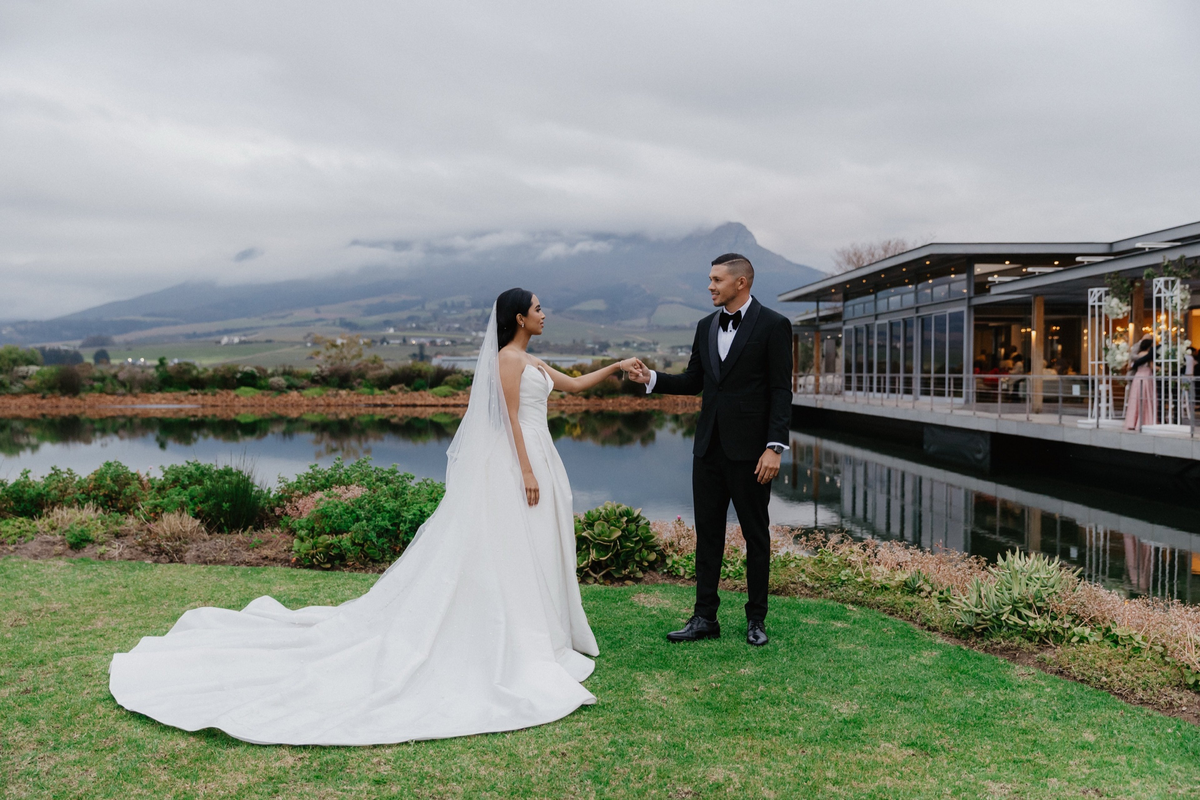 Bride and groom standing next to a dam on a grass area
