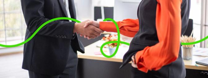 Two businesspeople, a woman and a man, shaking hands in agreement, symbolizing a promise or deal made between them.