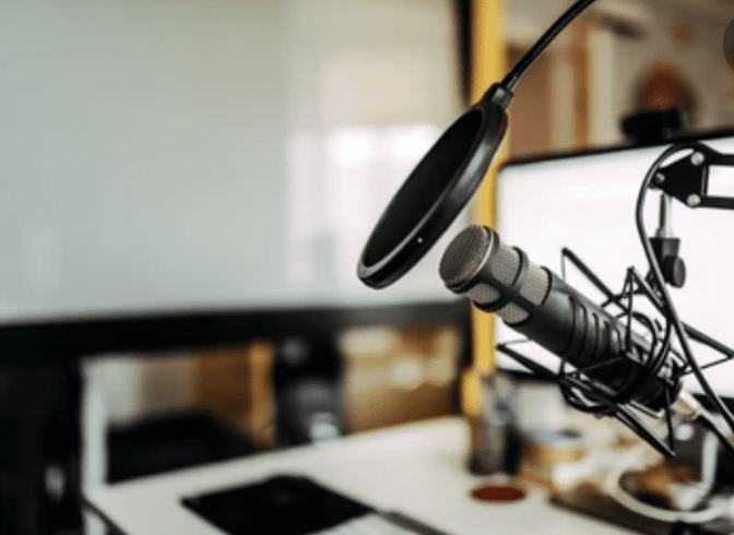 A black microphone sits on a desk next to a laptop computer.