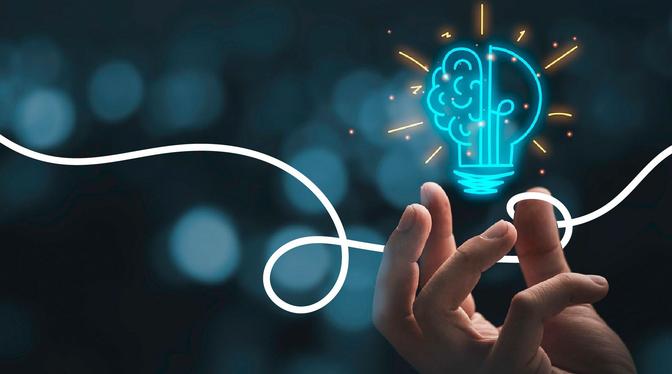 A hand holding a light bulb with a brain drawn on it. This suggests that the person is trying to come up with a new idea.