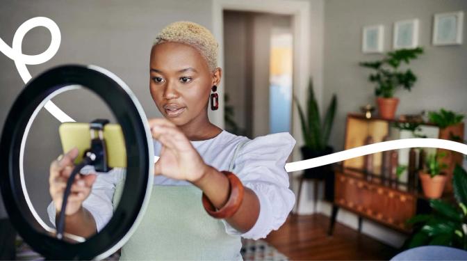 A woman smiling and holding a phone, taking a selfie.