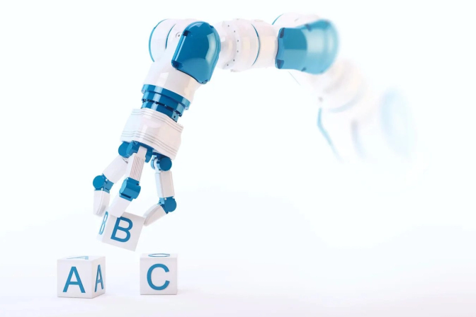 A robotic arm carefully stacks colorful blocks with letters on them. The letters spell out