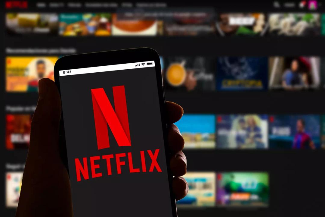 A person holding a smartphone with the Netflix logo on the screen.