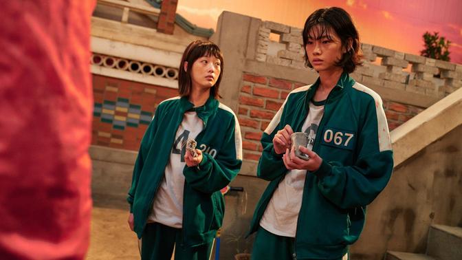 Two young people standing in front of a building. A scene from the Squid Game series on Netflix.