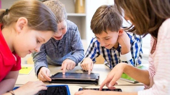 Four children around a table engaging with tablets, possibly during a classroom activity.