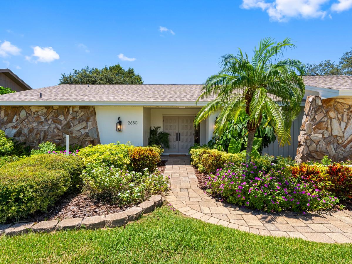 Front exterior of renovated Clearwater home with landscaped entry, stone facade, and walkway