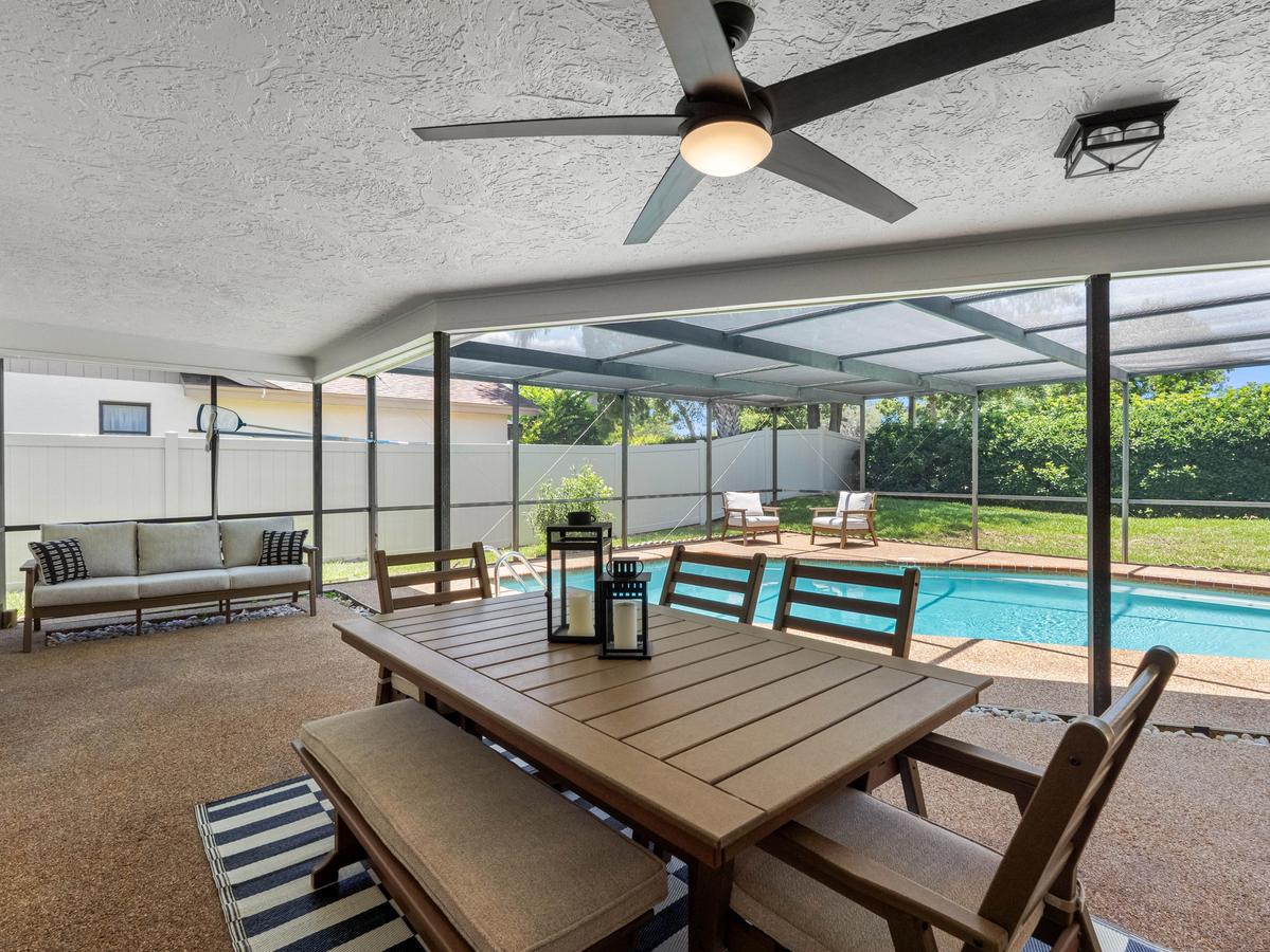 Covered outdoor patio with dining area, seating, and screened-in pool in Clearwater home