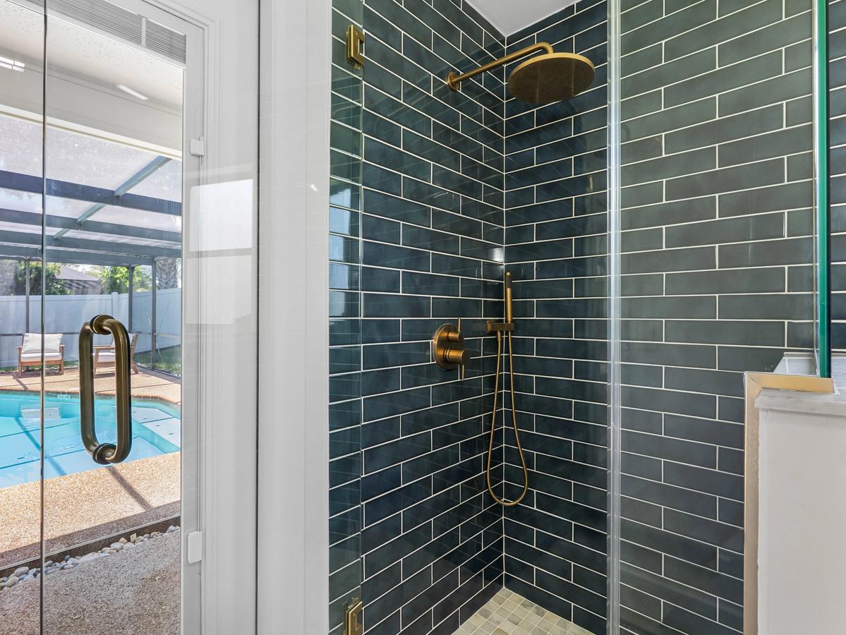 Walk-in shower with dark green tile, glass enclosure, and brass fixtures