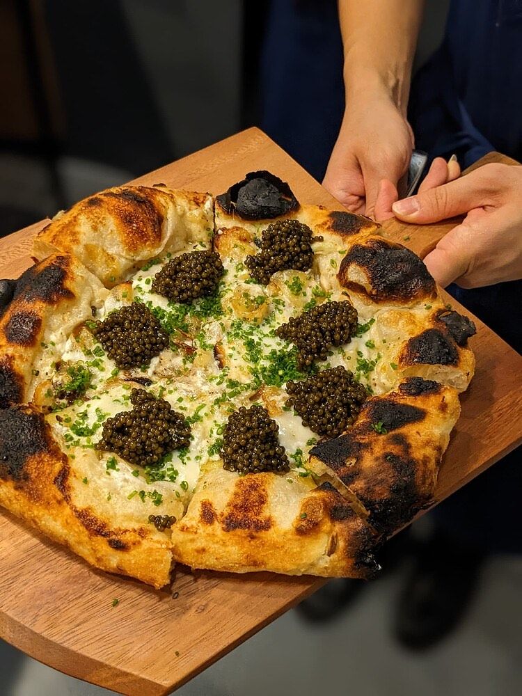 Patate pizza topped with Astrea caviar, served on a wooden board